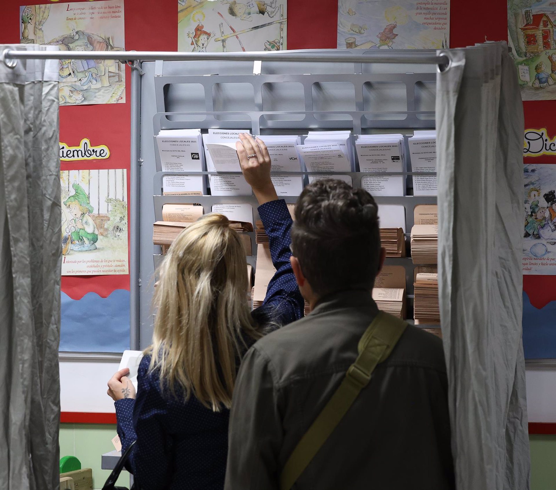 Electores españoles consultando las listas en un colegio electoral