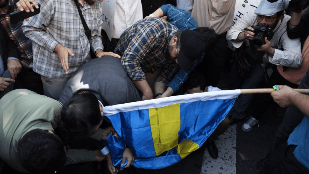 Un grupo de manifestantes quema una bandera sueca en Teherán