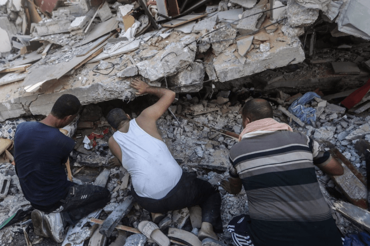 Palestinos buscando víctimas entre los escombros de un edificio en la Franja de Gaza