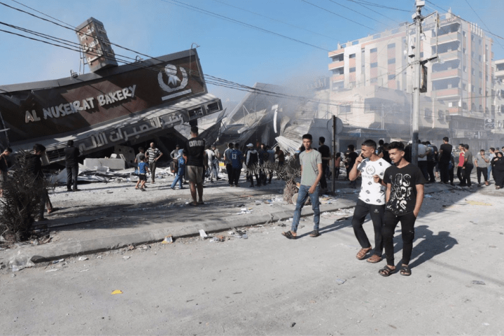 Un grupo de palestinos frente a una panadería destruida por un bombardeo de Israel