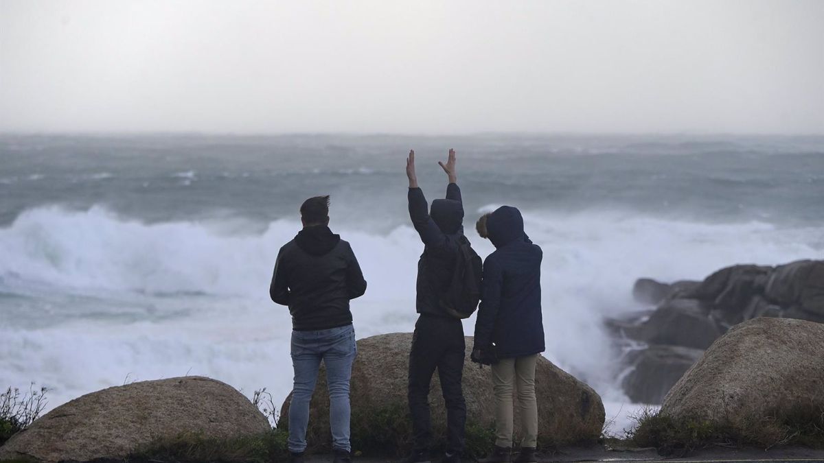 Tres jóvenes miran y fotografían el mar embravecido