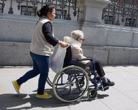 Una mujer mayor en silla de ruedas y su cuidadora