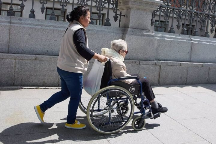 Una mujer mayor en silla de ruedas y su cuidadora