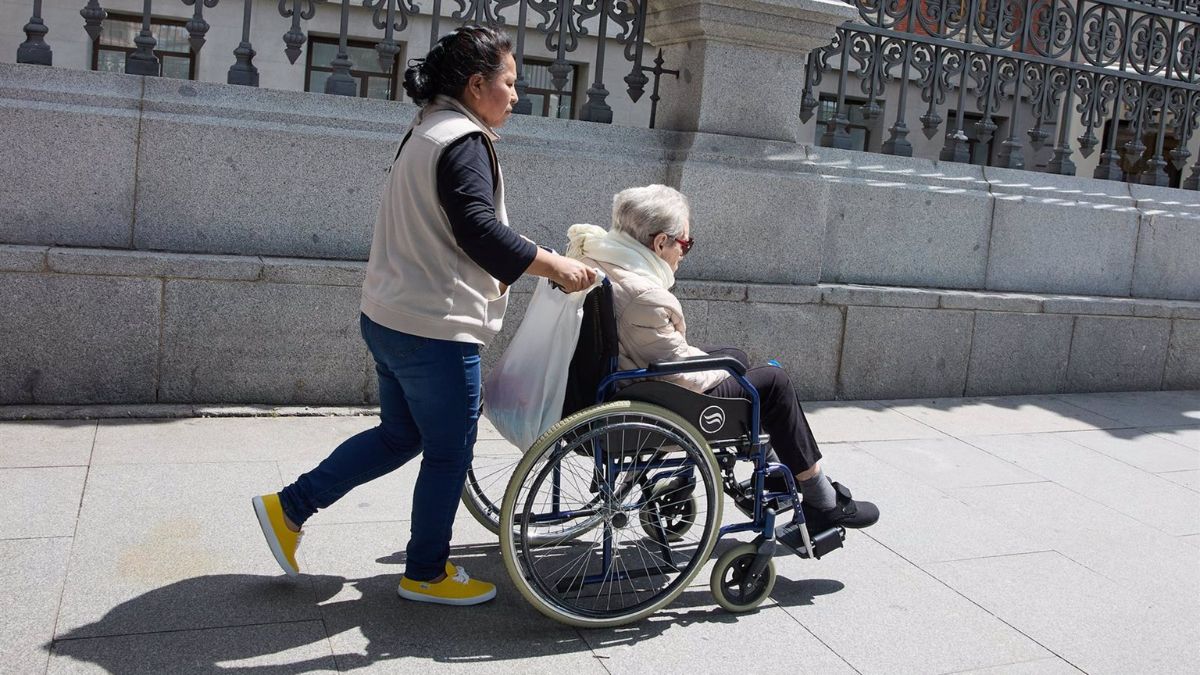 Una mujer mayor en silla de ruedas y su cuidadora