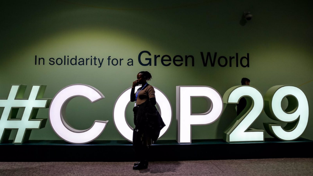 Una clmático desarrollo mujer pasa junto al logo de la COP29 en el Estadio Olímpico de Bakú. Foto: Dominika Zarzycka / DPA