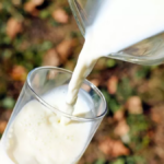 Persona sirviendo un vaso de leche pasteurizada