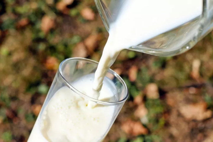 Persona sirviendo un vaso de leche pasteurizada