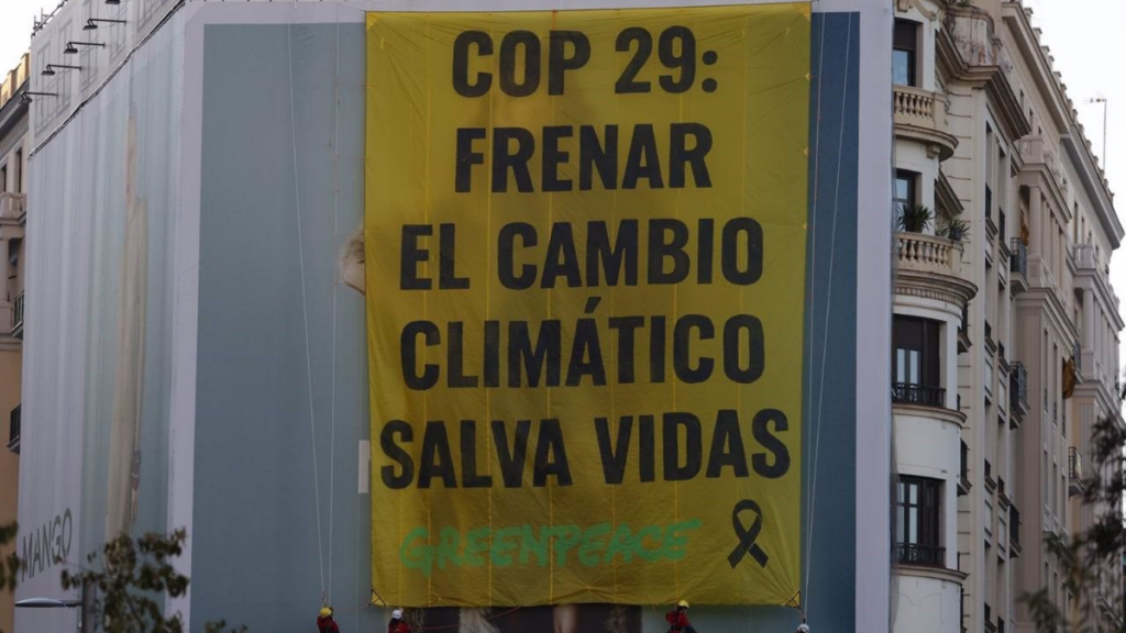 Activistas de climático Greenpeace despliegan la pancarta en la plaza de España de Madrid