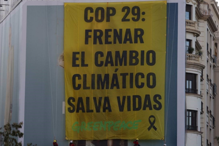 Activistas de climático Greenpeace despliegan la pancarta en la plaza de España de Madrid