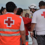 Trabajadores de la Cruz Roja atienden a los 190 migrantes rescatados por una embarcación de Salvamento Marítimo tras llegar anoche en una patera