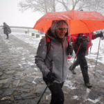 Una nieve y vientos persona camina con bastones y ropa de abrigo mientras nieva en la parroquia de O Cebreiro | EP