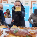 Varias personas cortan el roscón de reyes de Aldeas Infantiles